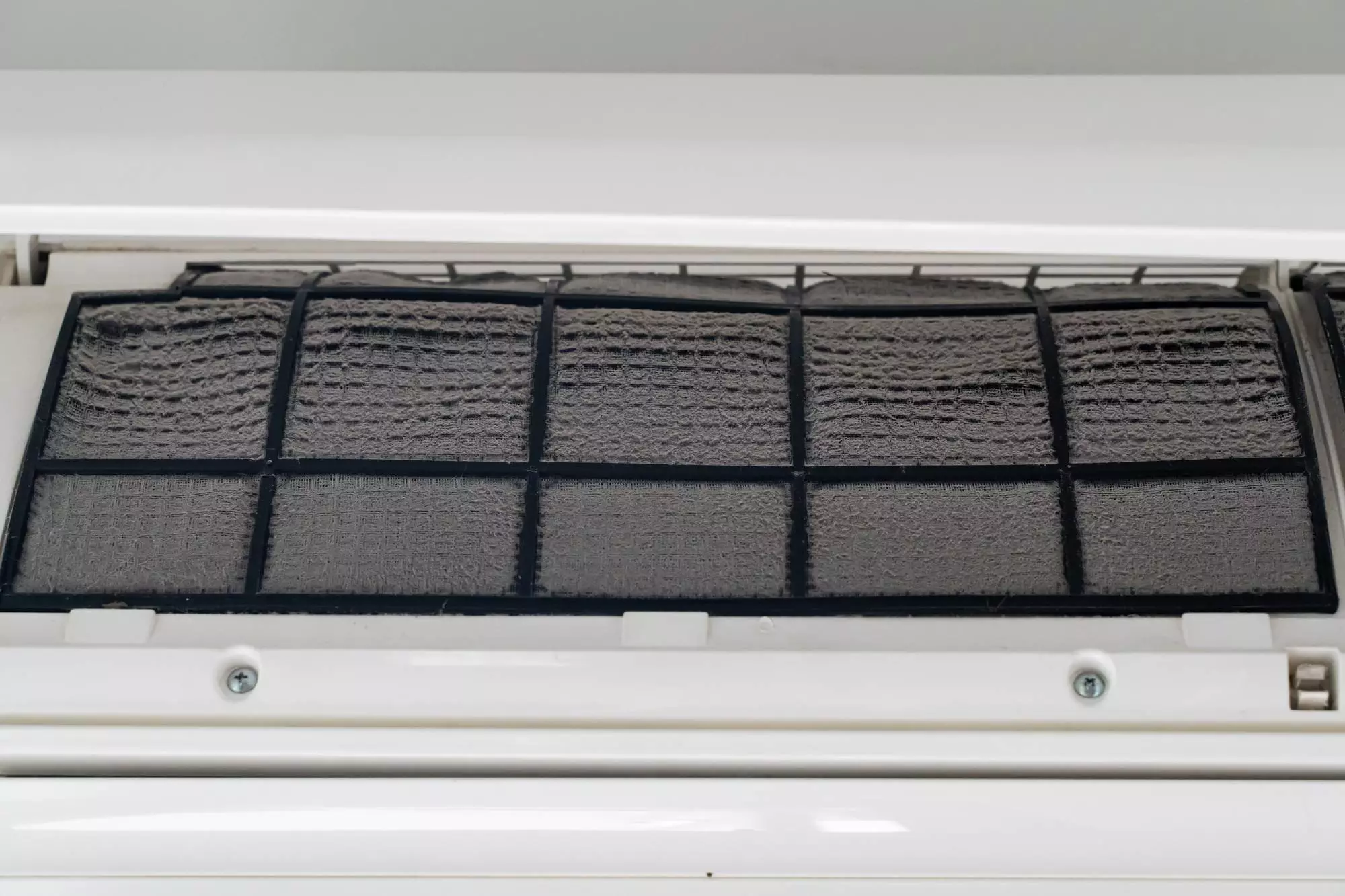 Close-up of an air conditioner filter covered in dust and dirt, indicating it needs cleaning or replacement for proper air conditioning function or to avoid the need for AC repair.
